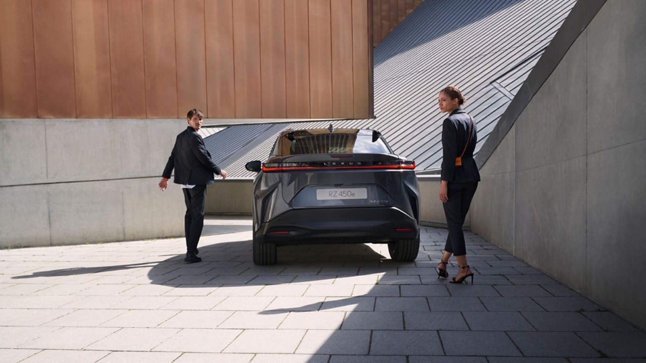 Two people walking towards a parked Lexus RZ